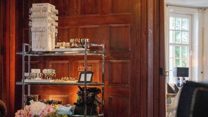 A wooden-paneled room with a bookshelf, a table with a vase of flowers, and a chair. - Hotel Dannegården Trelleborg (Trelleborg)
