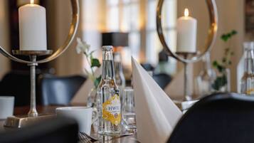A dining table with candles, a bottle of H.WILA Citron Liqueur, and a mirror.
