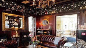 A cozy living room with a leather sofa, a zebra-patterned armchair, a chandelier, and a mirror. - Hotel Dannegården Trelleborg (Trelleborg)