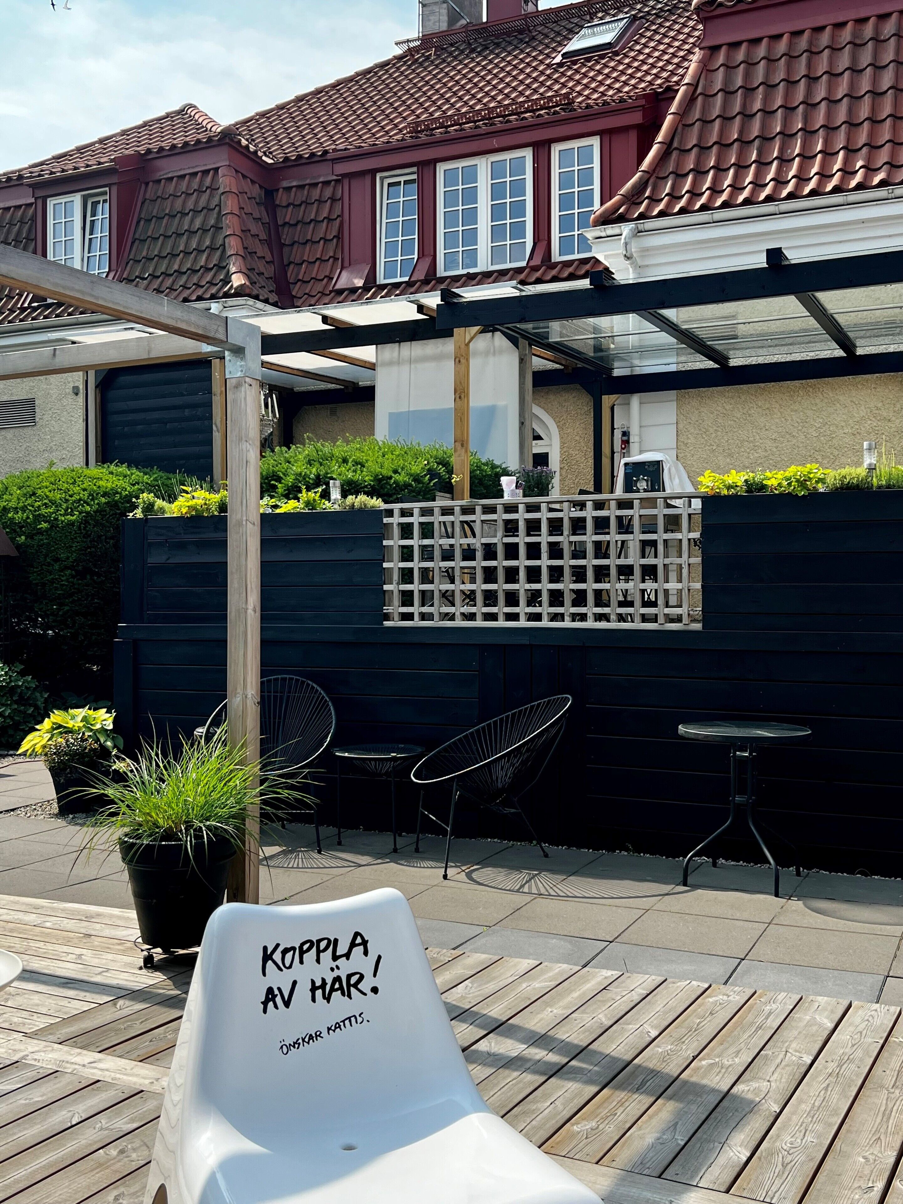 A wooden deck with a white chair, a black table, and a metal chair.
