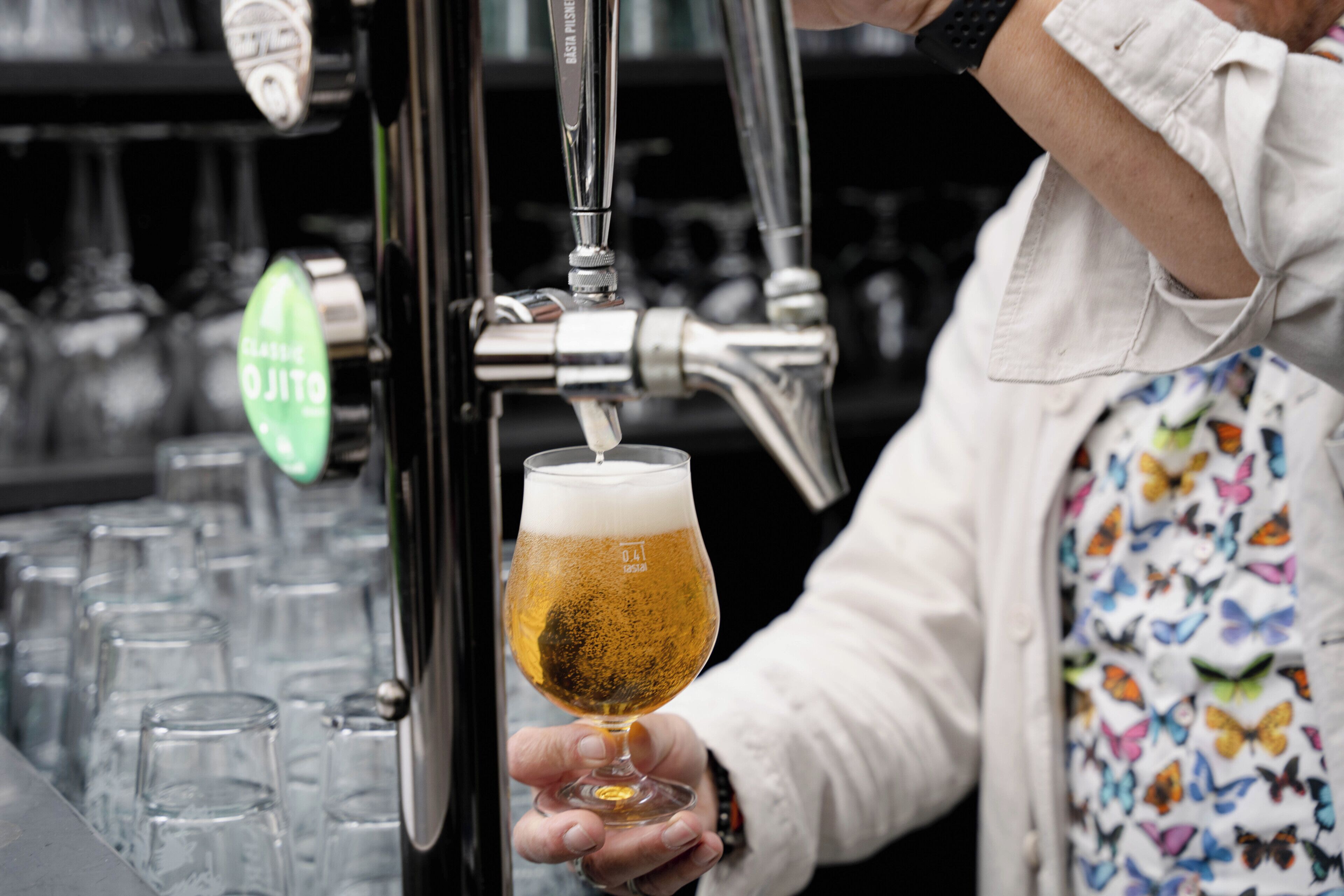 A person holding a glass of beer at a bar.