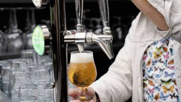 A person holding a glass of beer at a bar.