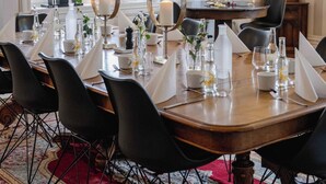 Un comedor con una mesa redonda, sillas negras, una alfombra roja y un ventanal grande.