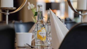 Un tavolo da pranzo con una candela, una bottiglia di HWIIL citrus, una tazza bianca e un tovagliolo.