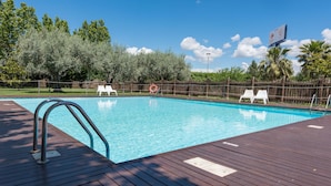 A swimming pool with a wooden deck, metal pool ladder, and white lounge chairs. - Hotel Las Ventas (Utebo)