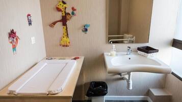 Un baño con lavamanos, espejo y un pequeño cubo de basura.