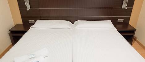 A hotel room with a double bed, two nightstands, and two wall-mounted lamps.