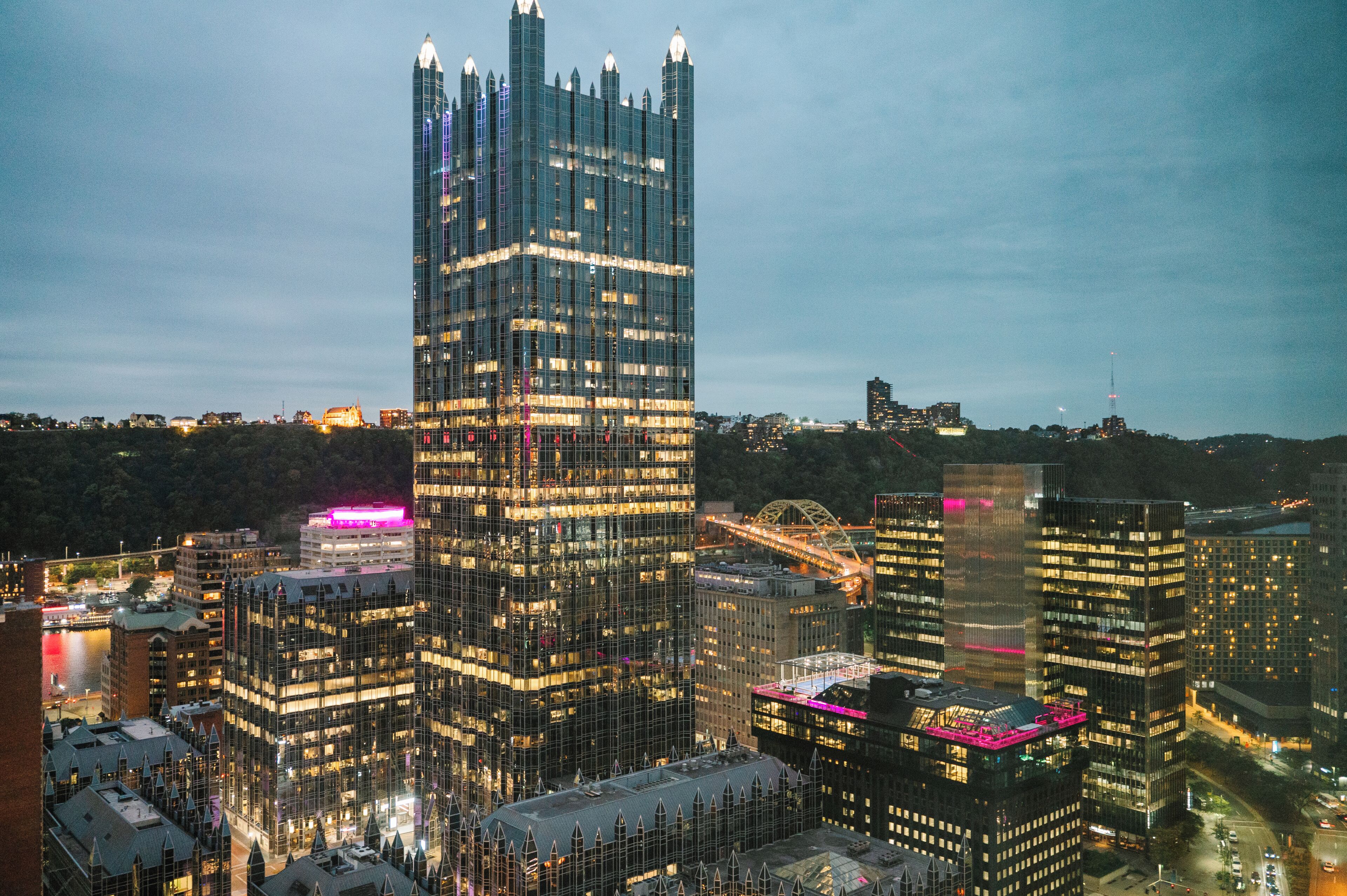 Ein Hochhaus mit moderner Glasfassade, umgeben von weiteren Gebäuden und einer Brücke.