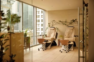 A modern room with two massage chairs, a large window, and a view of a building.