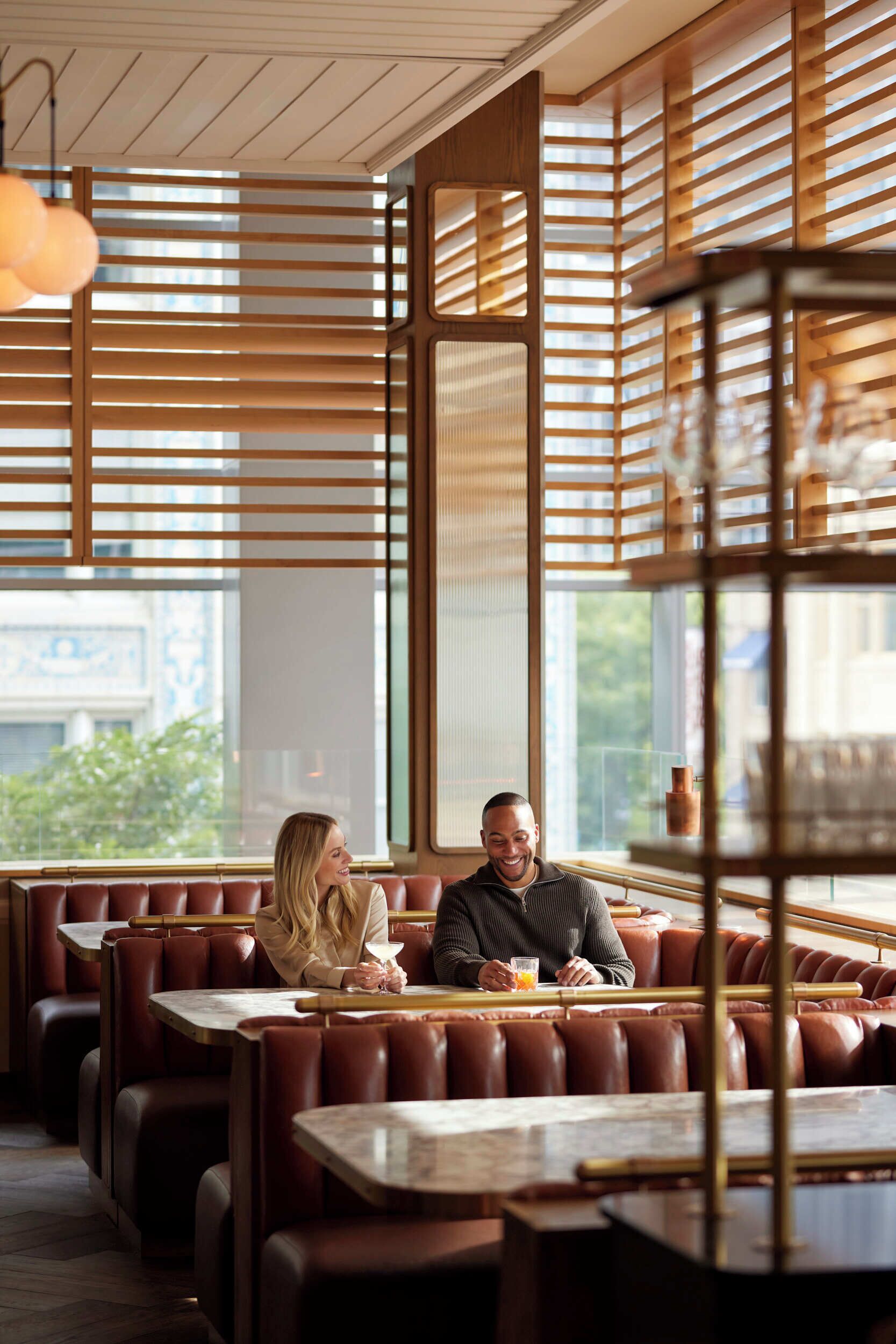 Un restaurante con paredes de listones de madera, asientos de cuero y un amplio ventanal con vistas a la ciudad.