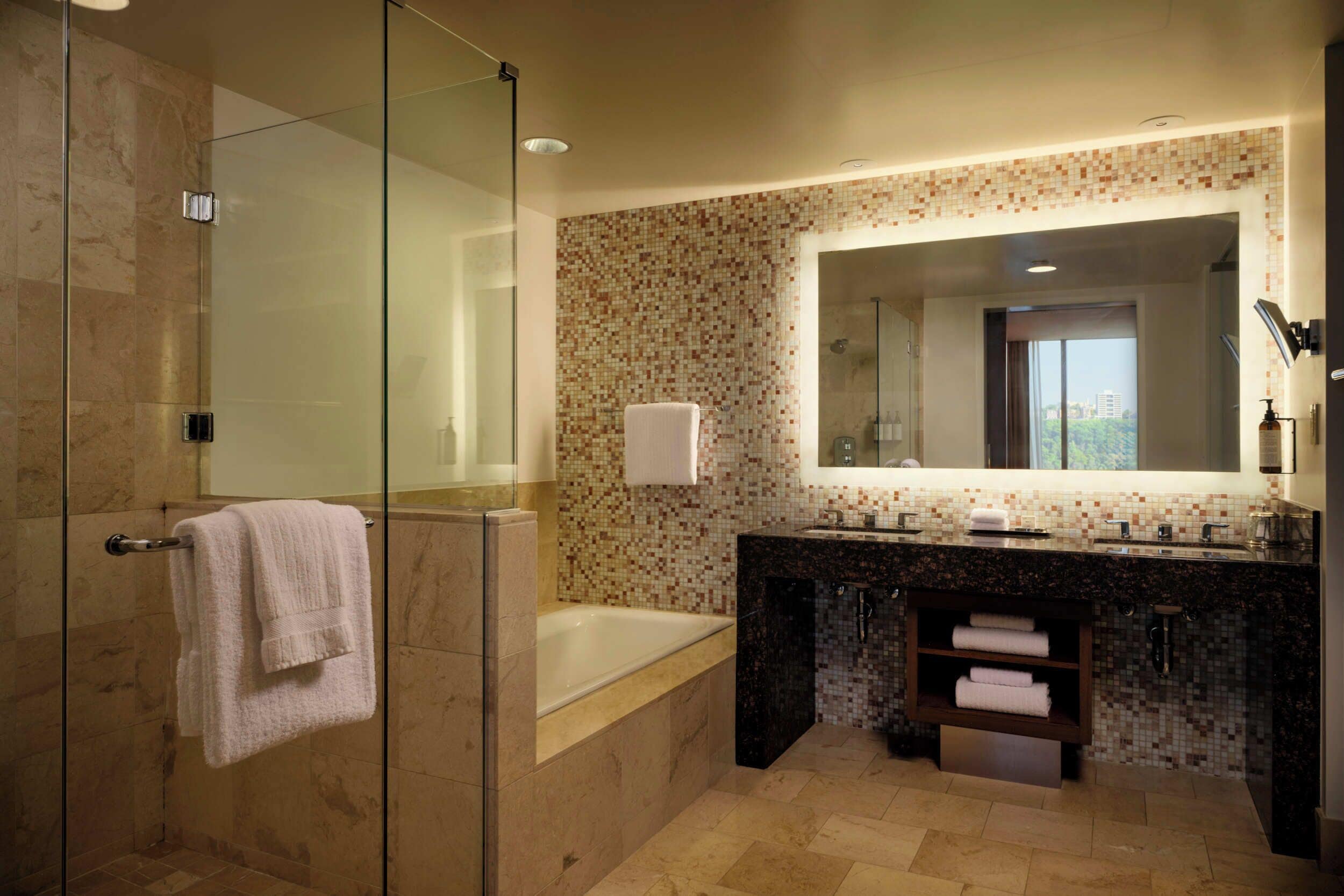 Un baño moderno con cabina de ducha de vidrio, bañera, tocador con espejo y salpicadero de azulejos.