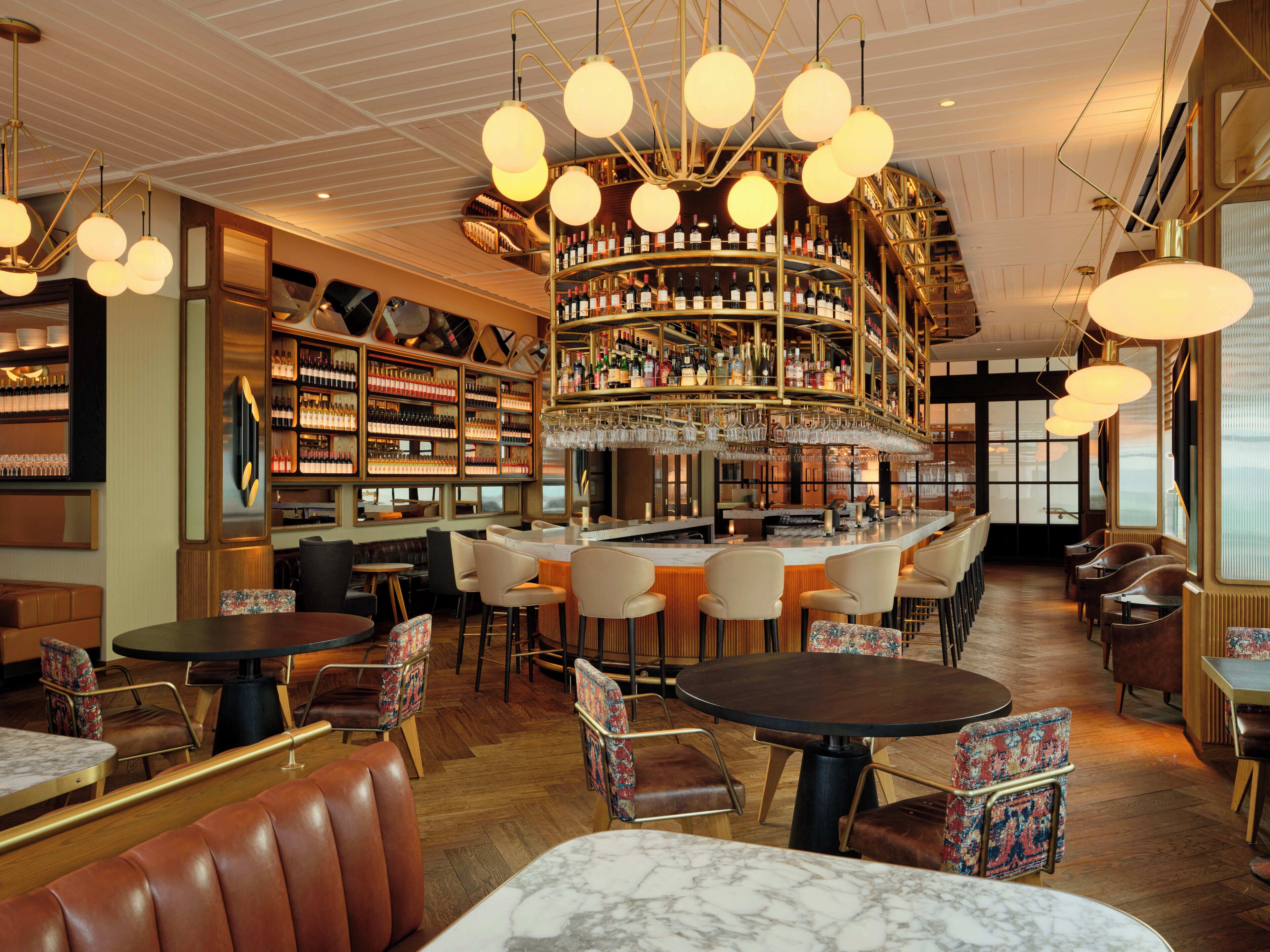 Zona de bar con varias opciones de asientos, incluyendo taburetes y sillas, y una exhibición de vinos.