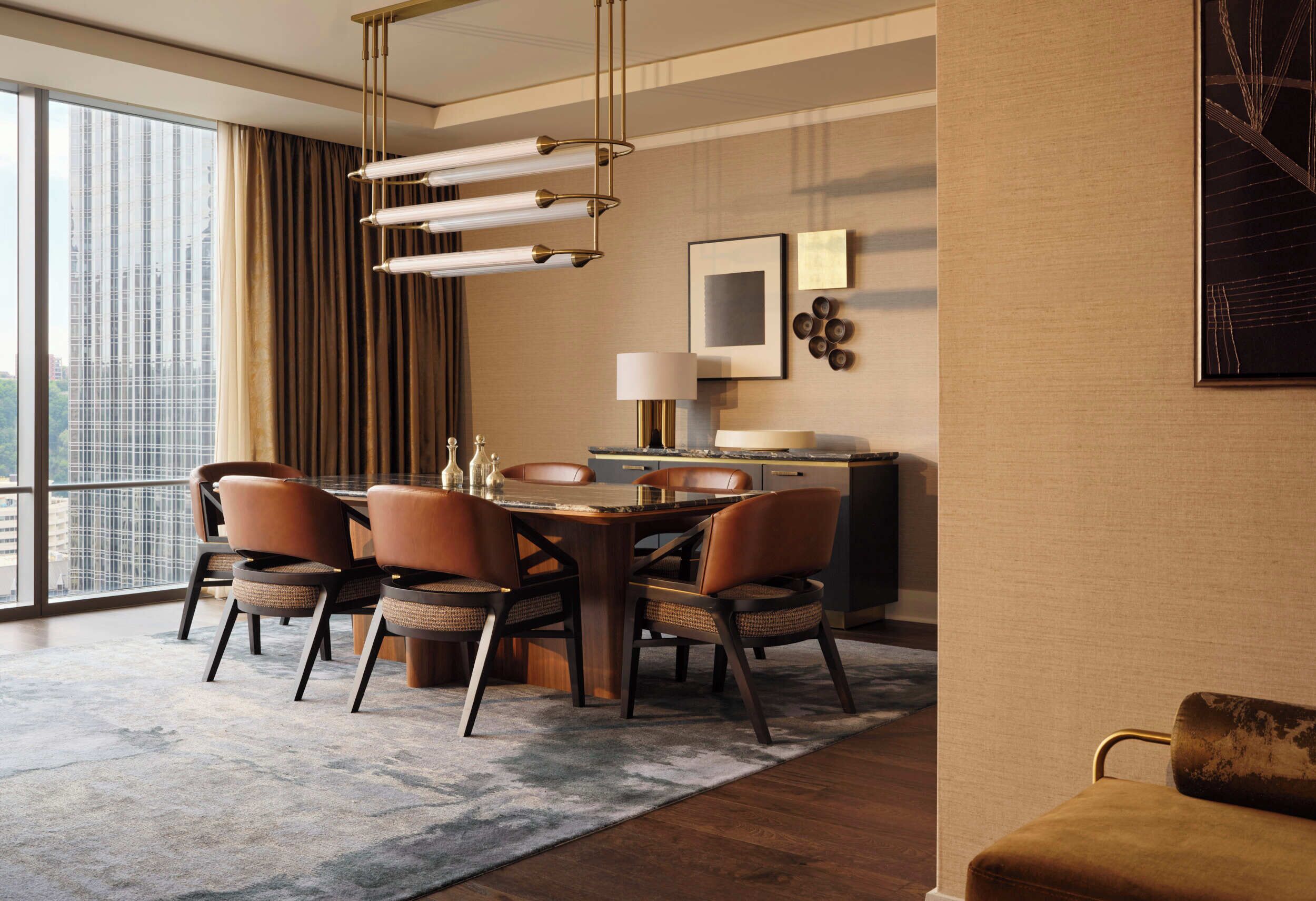 A modern dining area with a wooden table, leather chairs, and a city view through large windows.