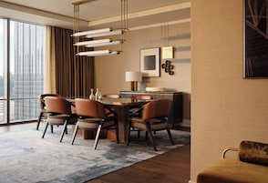 Un comedor moderno con una mesa de madera, sillas de cuero y vistas a la ciudad a través de amplios ventanales.