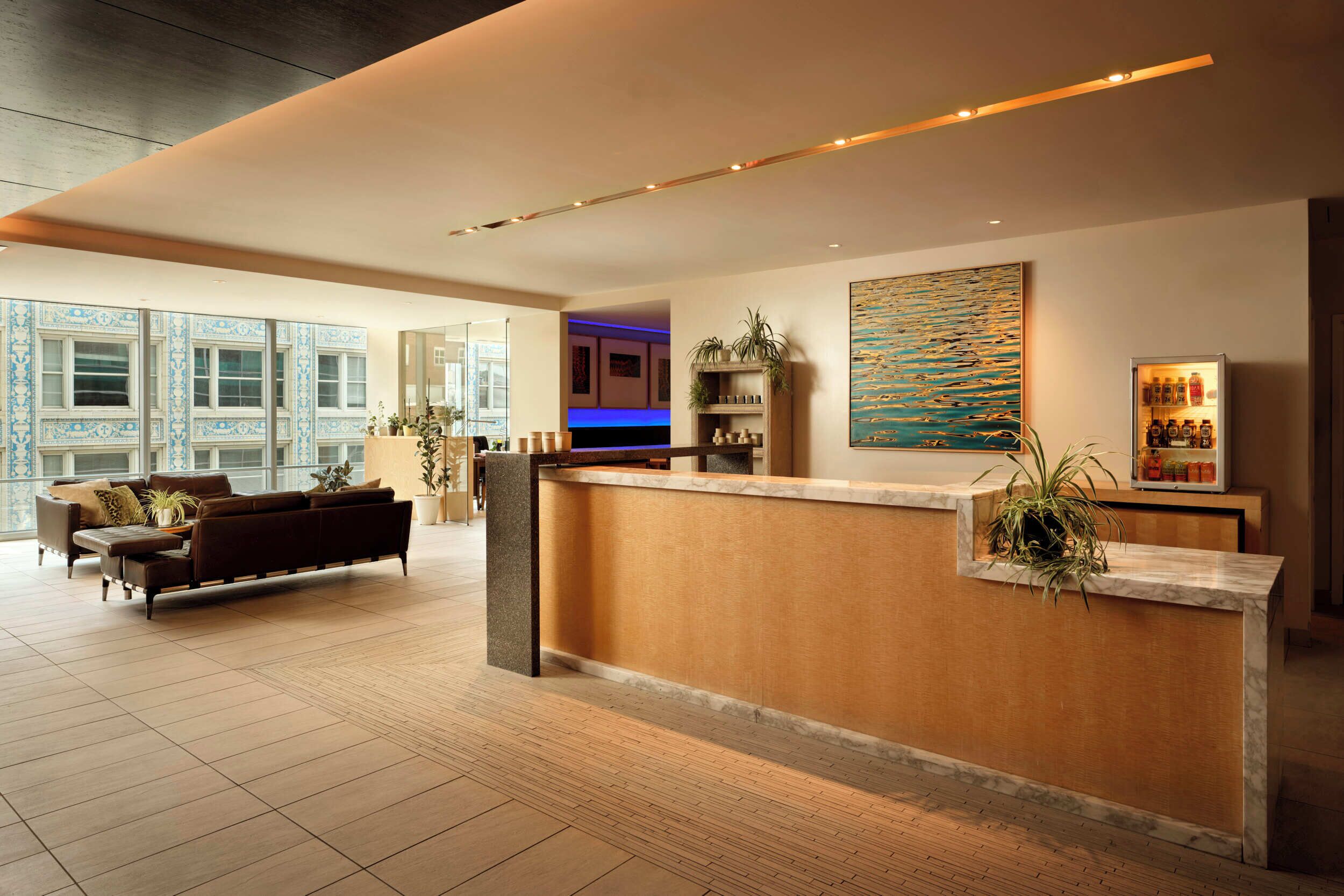 Un moderno vestíbulo de hotel con mostrador de recepción, zona de estar y grandes ventanales.