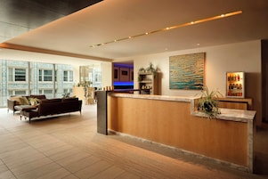 Un moderno vestíbulo de hotel con mostrador de recepción, zona de estar y grandes ventanales.