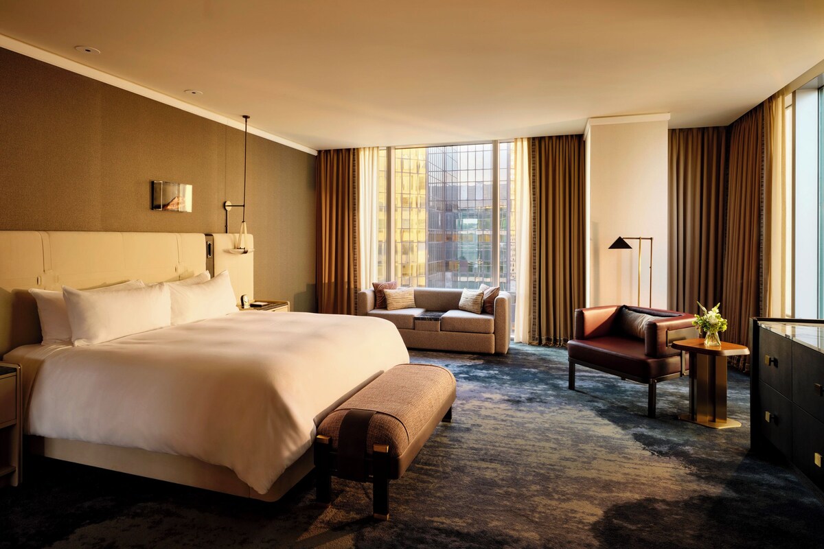 Une chambre d’hôtel avec un grand lit, un canapé, un bureau et une commode.