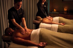 Una sesión de terapia de masajes en una sala con poca luz, con una camilla y un terapeuta atendiendo a un cliente.