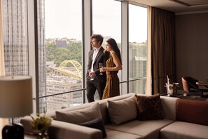 Una habitación de hotel moderna con un ventanal grande, un sofá y un comedor.