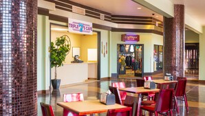 Un espacio interior amplio con una cafetería llamada 'Triple 7's Café' y una tienda de ropa llamada 'Cocorah'.