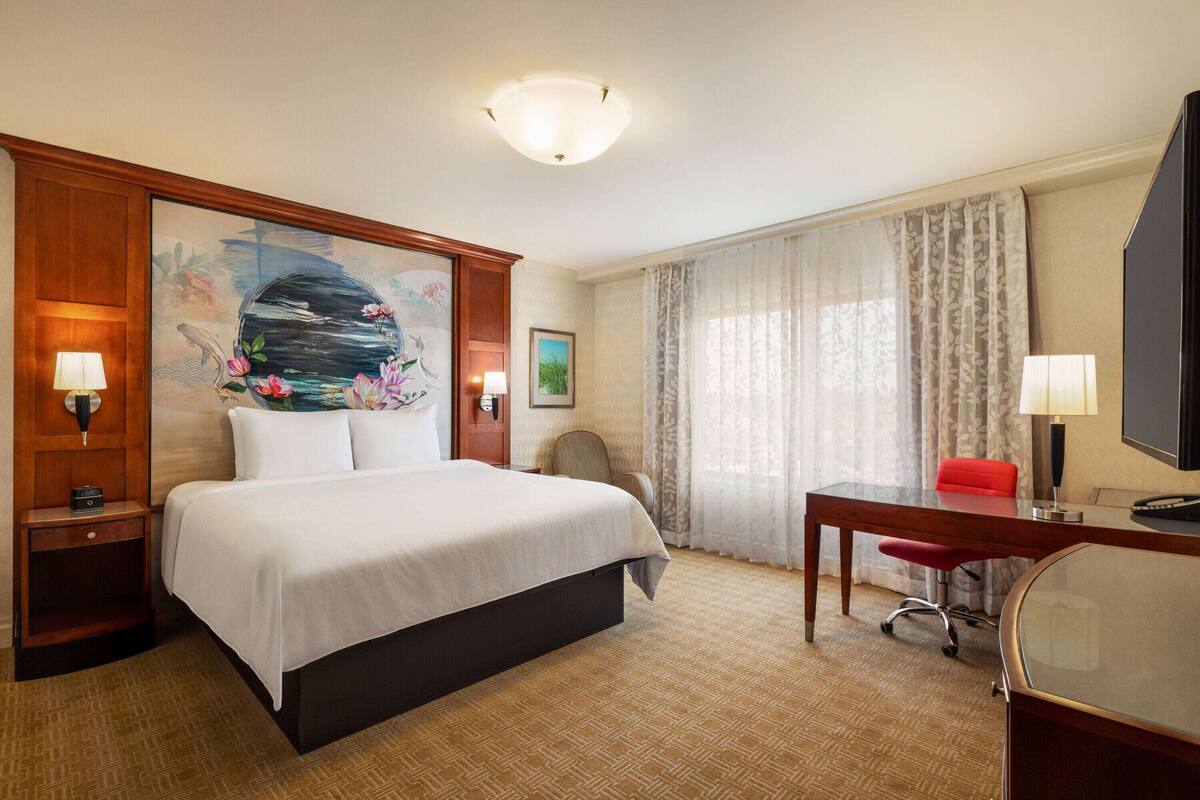 Een hotelkamer met een groot bed, een bureau, een stoel en een televisie.