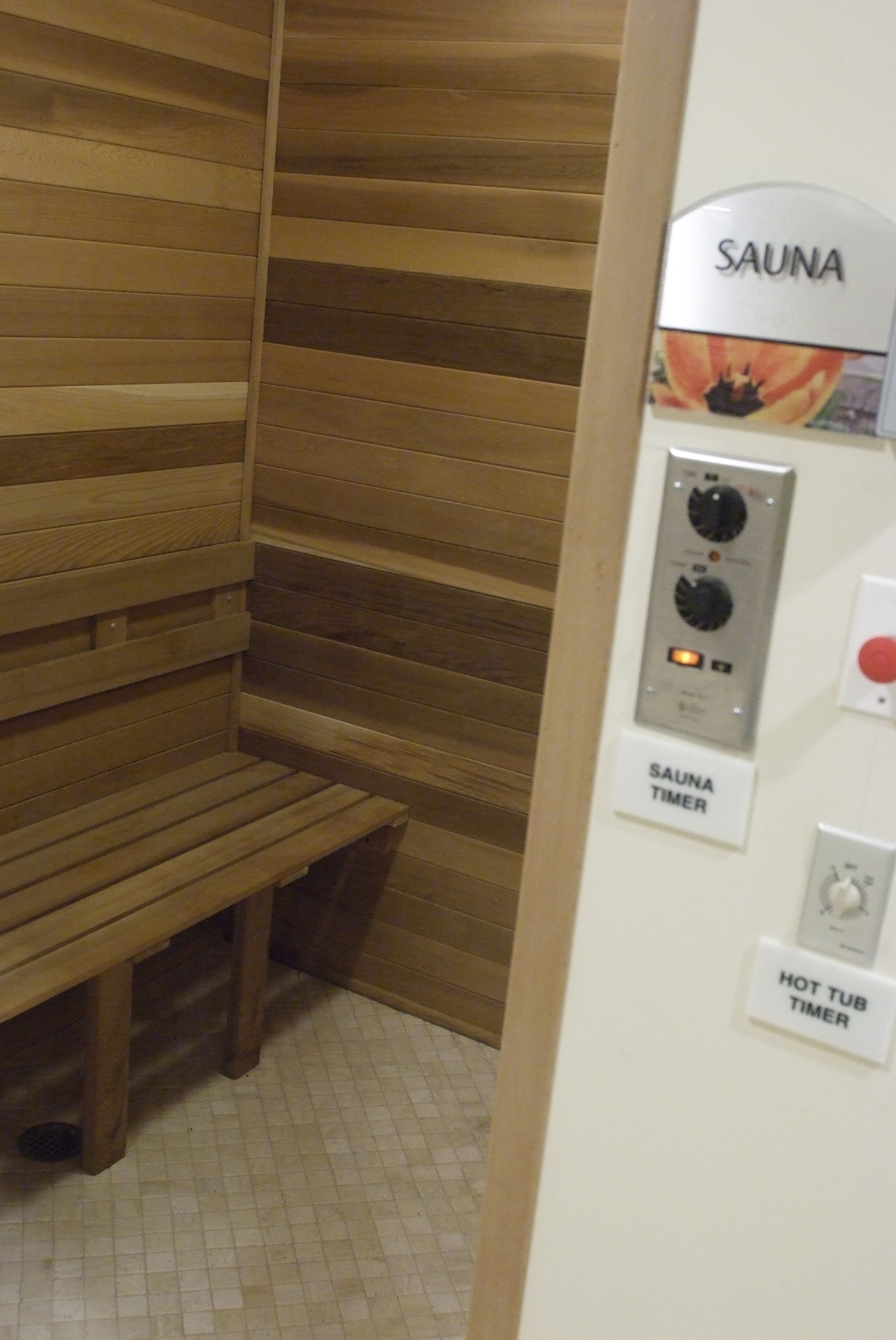 Ein Saunaraum mit einer Holzbank, einem Sauna-Timer und einem Timer für das Whirlbad.