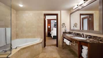 A hotel bathroom with a bathtub, two sinks, and a large mirror.