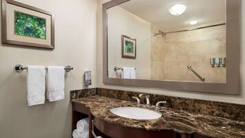 A bathroom with a marble sink, a large mirror, and two framed pictures on the wall.