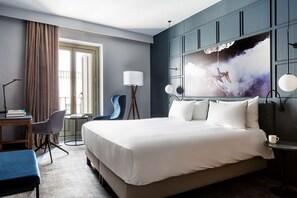 A hotel room with a large bed, a desk with a chair, a small table, and a large window with curtains. - Radisson Blu Boutique Hotel, Madrid Prado (Madrid)