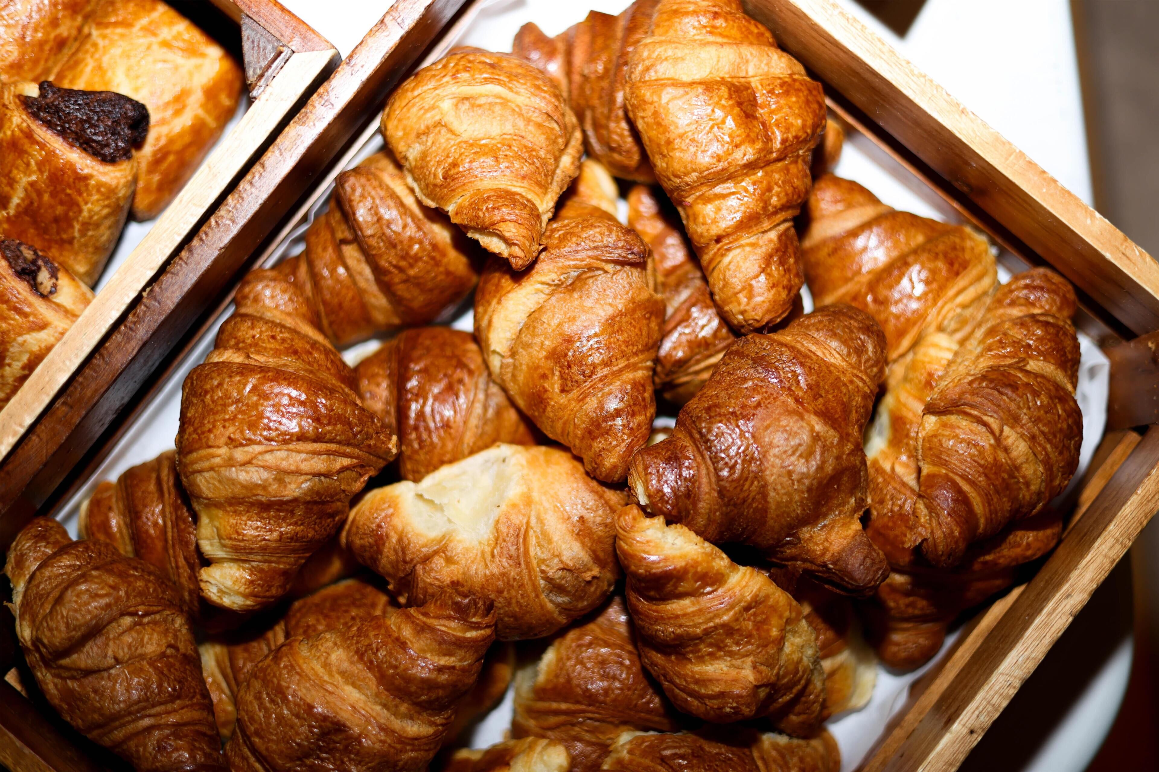 Diverse gebakjes, waaronder croissants en chocoladegebak, gepresenteerd in houten dozen.