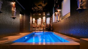 Ein modernes Hallenbad in Blau, umgeben von strukturierten Wänden und dekorativer Beleuchtung.