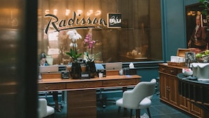 Un interior moderno con techo de vidrio, escritorios de madera y un letrero de Radisson.