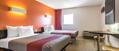 A hotel room with two beds, a desk, and a TV.