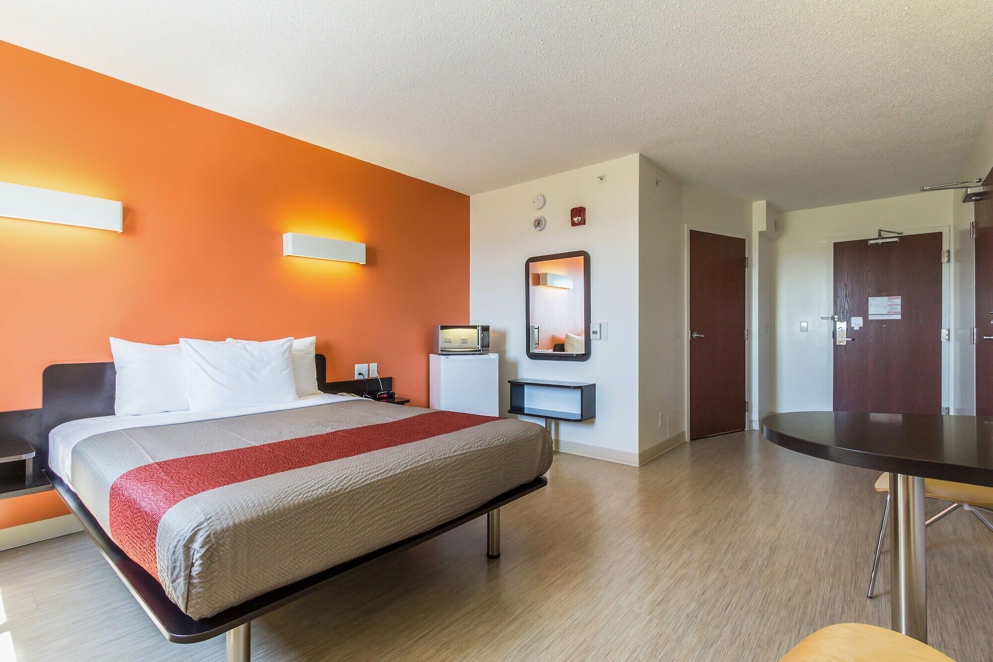 Una habitación de hotel con cama, mesita de noche y escritorio con silla.