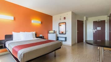 Una habitación de hotel con cama, mesita de noche y escritorio con silla.