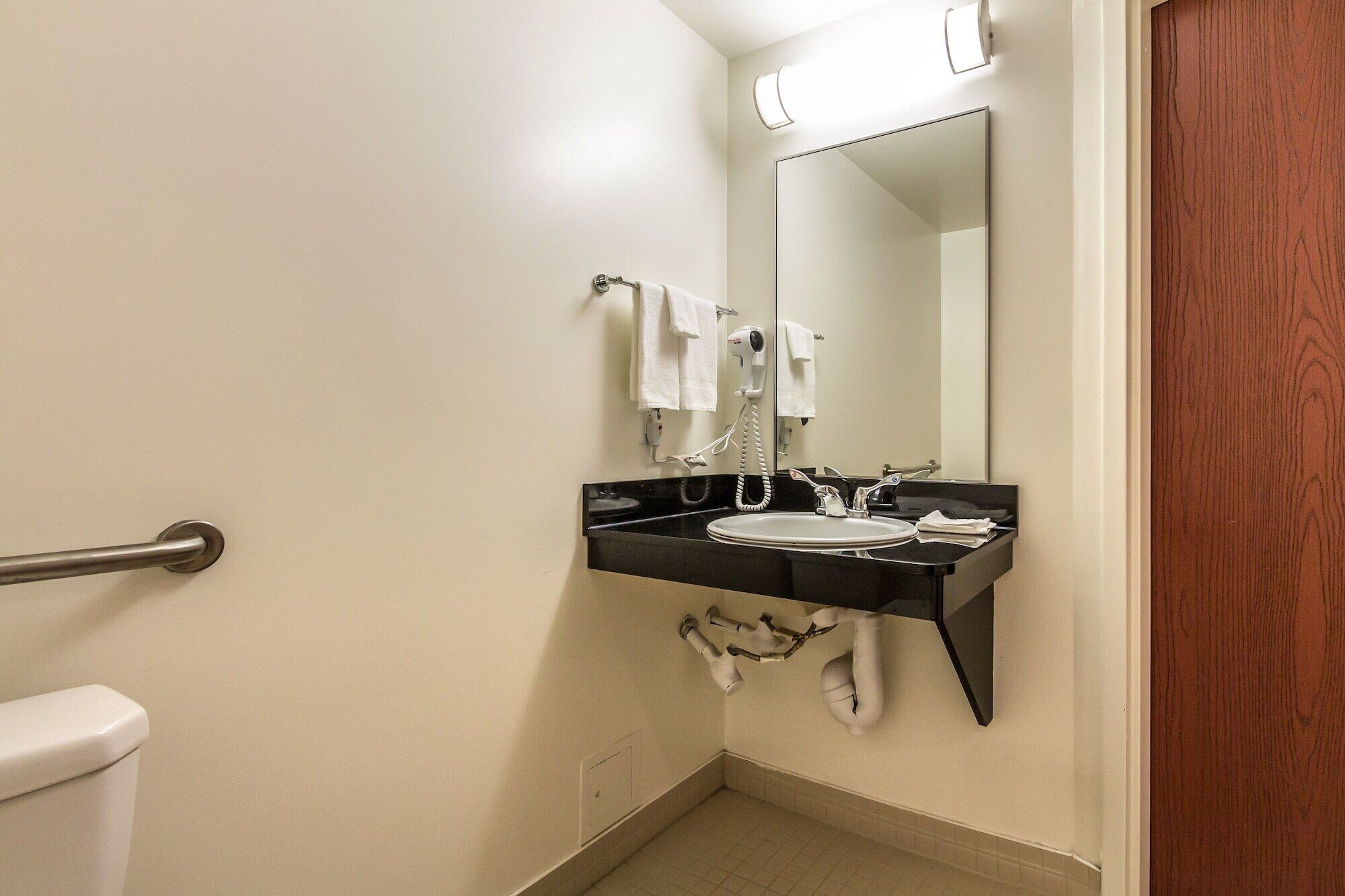 Ein Badezimmer mit Toilette, Waschbecken, Spiegel und Handtuchhalter.