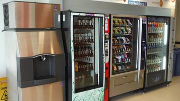 Four vending machines with various beverages and snacks, a caution wet floor sign, and a Marketplace sign above.