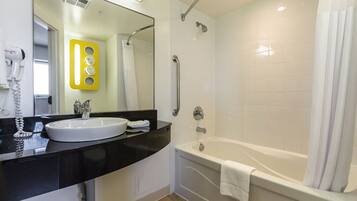 Un baño moderno con un lavamanos blanco, encimera negra y bañera blanca.