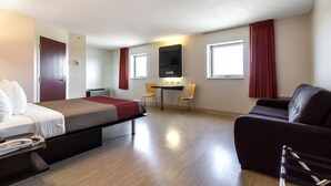 Una habitación de hotel con cama, escritorio, silla y sofá.