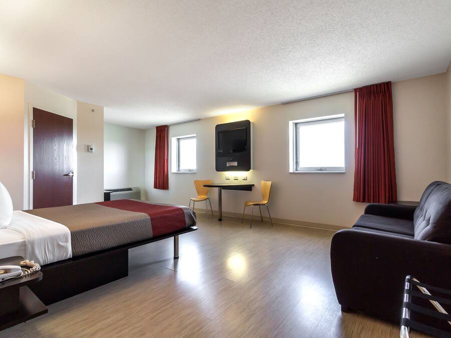 A hotel room with a bed, a desk, a chair, and a sofa.
