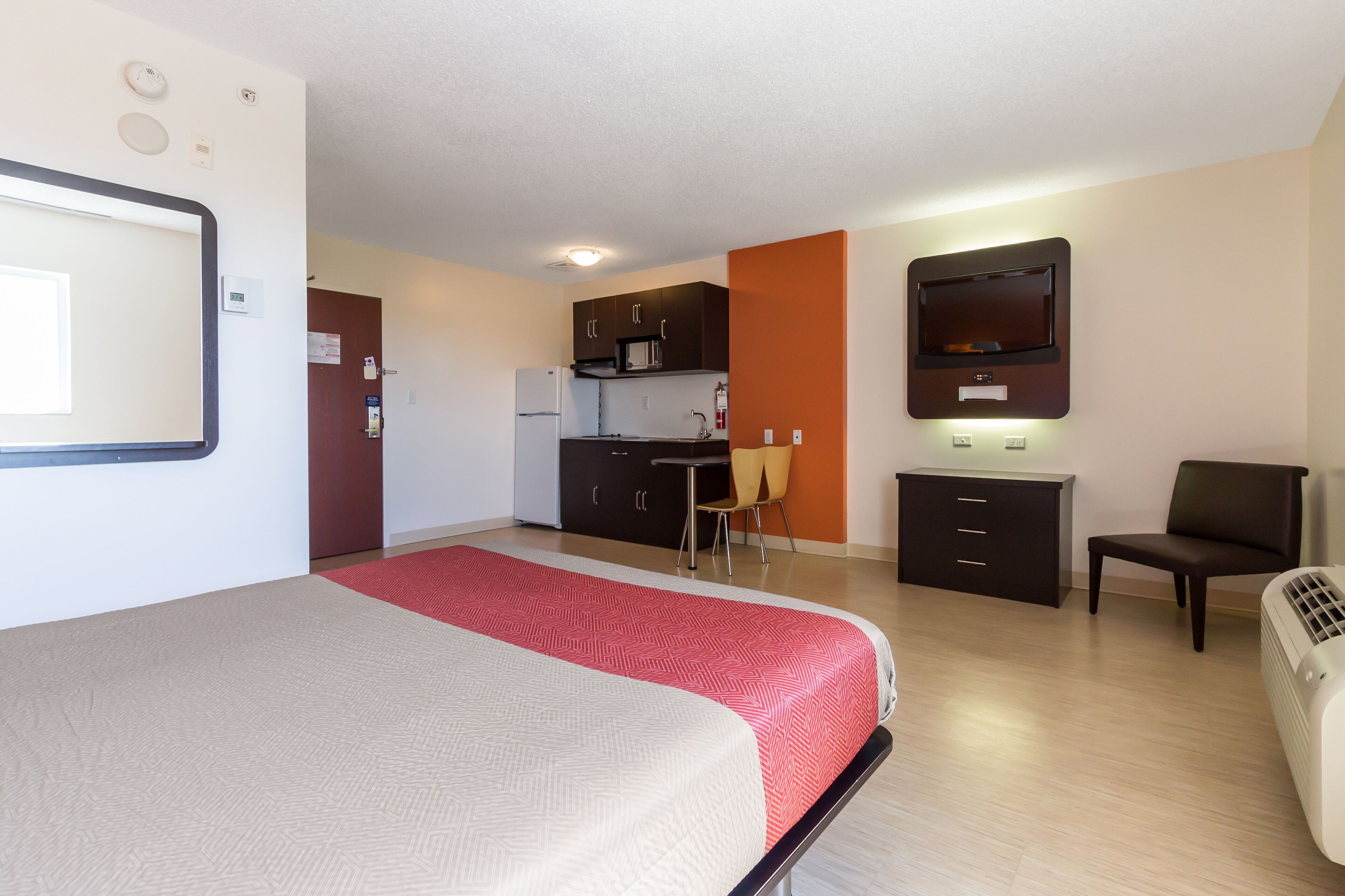 Une chambre d’hôtel équipée d’un lit, d’un bureau, d’une chaise, d’un four à micro-ondes et d’une télévision.