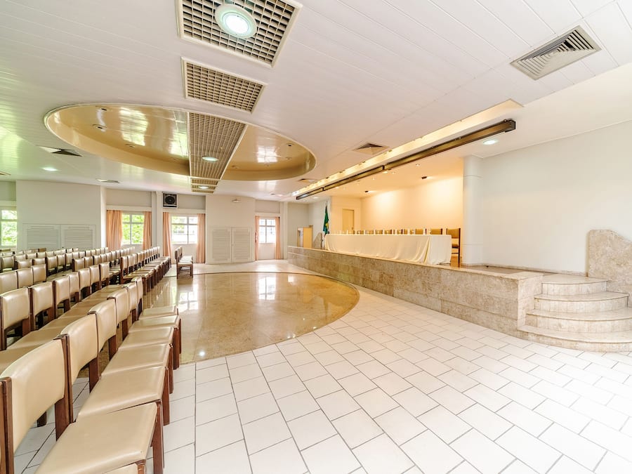 Un'ampia sala con file di sedie, una scalinata in marmo e una reception.