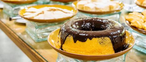 Un bufé con diversos postres, incluyendo un pastel cubierto de chocolate y otras opciones dulces.