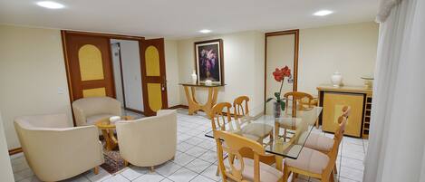 Un comedor con una mesa de vidrio, sillas de madera y un sofá.