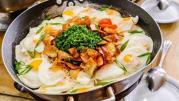 Diversos platos en sartenes sobre una mesa, incluyendo una sartén con huevos, verduras y carne.