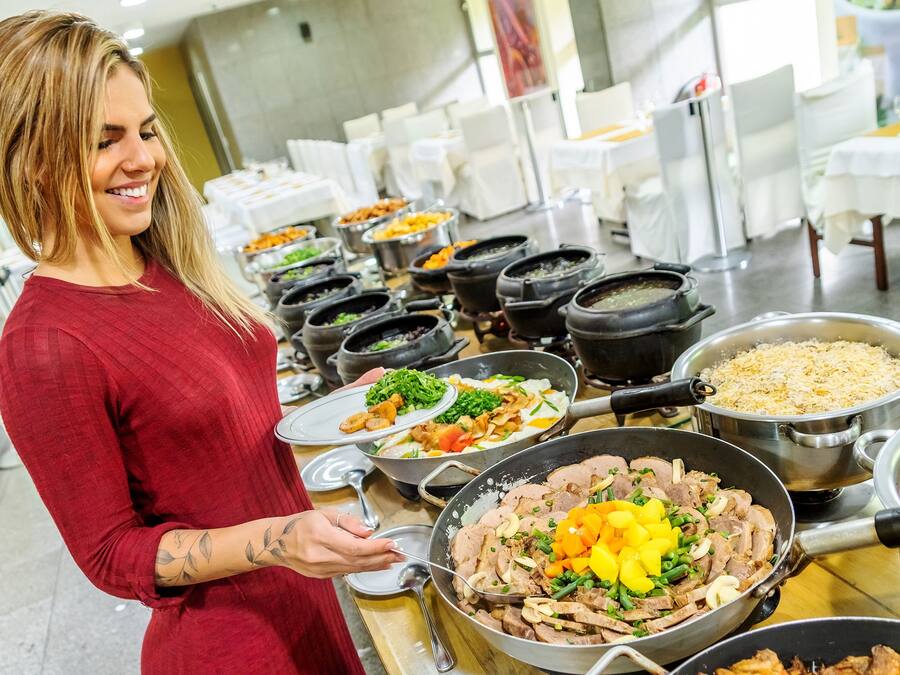 Un bufé con diversos platos, incluyendo carnes, verduras y arroz.