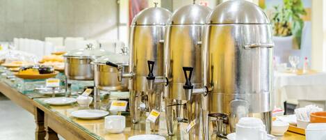 A buffet setup with multiple coffee dispensers and a variety of dishes.