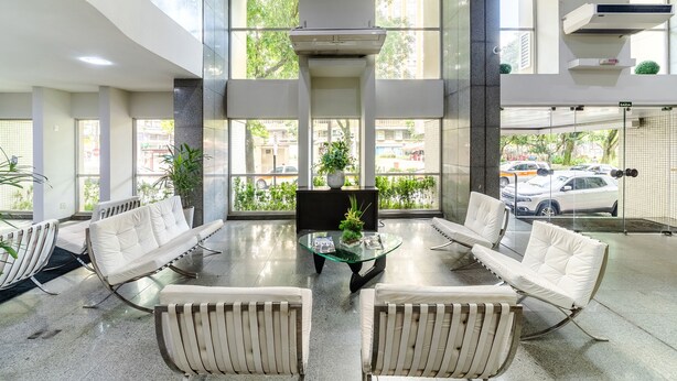 A spacious lobby with modern seating, large windows, and a central plant.