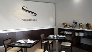 A restaurant with tables set for dining, a logo on the wall, and a counter with various items. - Hotel Europa (Utebo)