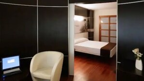 A modern room with a bed, a chair, and a desk with a laptop. - Hotel Europa (Utebo)
